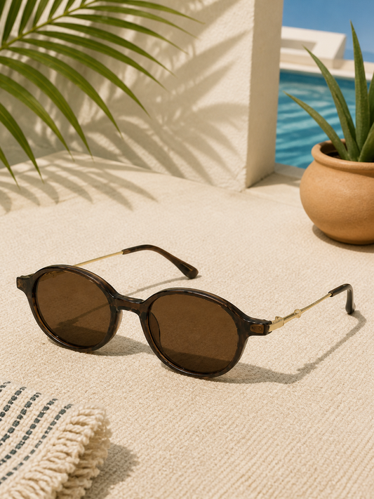 Sienna brown oval sunglasses in a sunlit resort setting