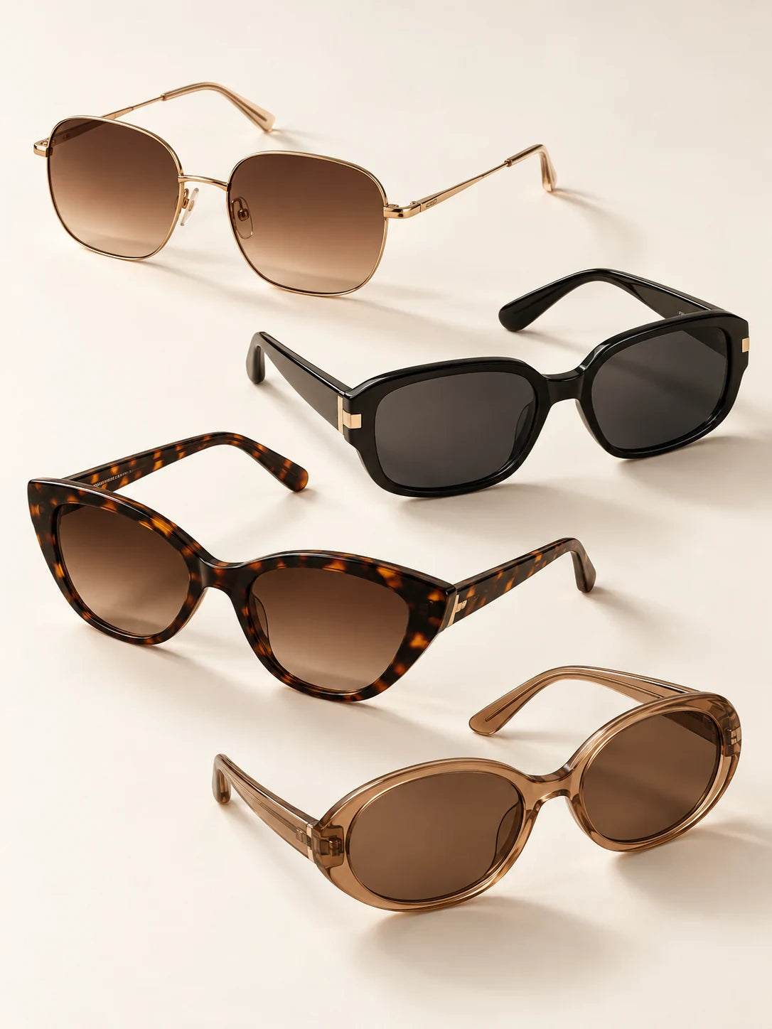 Four sunglasses in gold, black, tortoiseshell and translucent brown frames